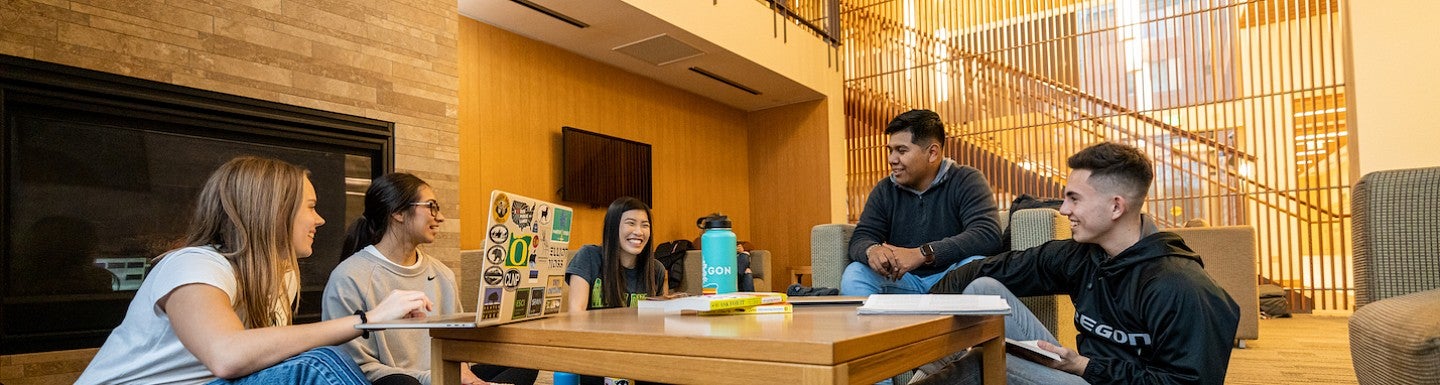 A group of students with books and a laptop seated around a low table