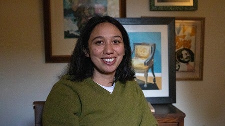 portrait of mary vertulfo sitting in front of framed artworks